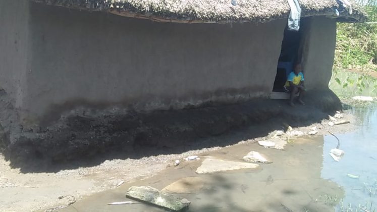 Child outside a mud-walled house.